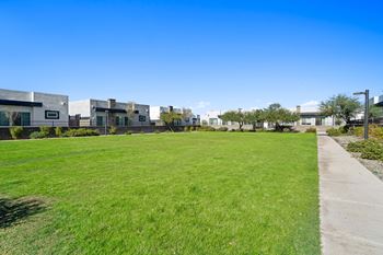 A green lawn in front of a row of apartment buildings
